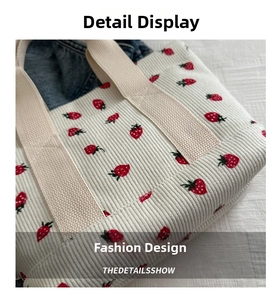 Detailed close-up of ivory corduroy tote bag with red strawberry print and sturdy handles