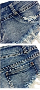 Detailansicht von Denim-Shorts mit ausgefransten Kanten und Metallnieten