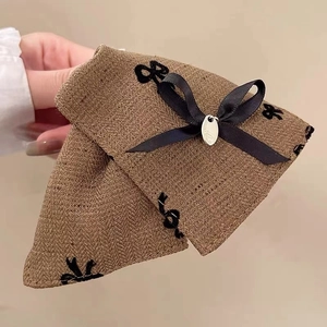Macro detail of retro brown herringbone fabric hair claw with black bow and silver tag