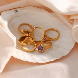 Elegant 18K gold-plated rings with purple and pink zircons displayed on a shell