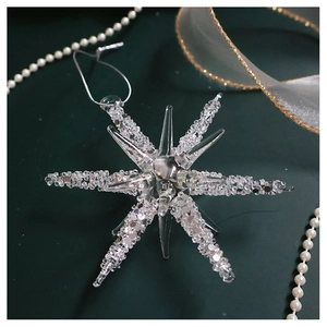 Macro shot of glass snowflake ornament with silver string on dark green backdrop