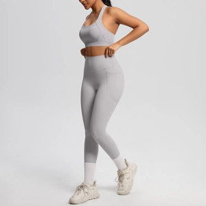 Detail view of high-waist light grey yoga leggings with functional side pocket and sports bra