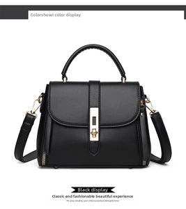 Front detail of black matte leather handbag with gold vertical buckle and metal studs