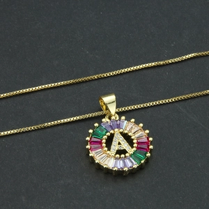 Macro shot of gold-plated letter A pendant necklace with colorful zircons on black background
