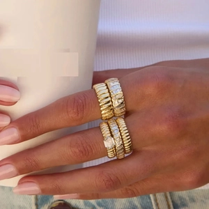 Close-up of stacked gold rings with twisted texture and micro-pave zircons on hand