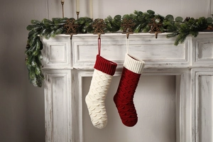 Detail of red and cream knitted Christmas stockings with fish scale pattern on a fireplace