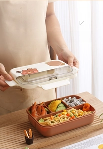 Detail of four-compartment bento box featuring cartoon bear print and sealed lid