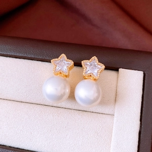 Macro shot of 18K gold star stud earrings with clear zircon and lustrous white pearls