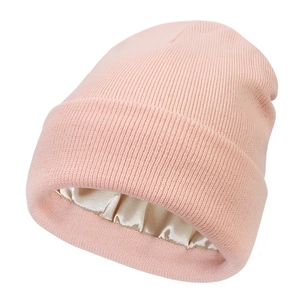 Detail view of pink knit beanie showing silk satin lining for hair protection and warmth