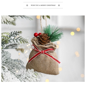 Detail of burlap Christmas gift bag with pine cones and berries hanging on tree branch