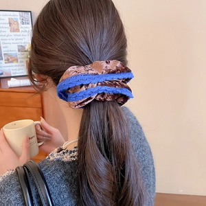 Detailed view of a brown and blue lace scrunchie worn on a ponytail in a cozy setting