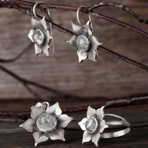 Vue détaillée d'une parure en argent floral avec pierres sur fond de bois rustique