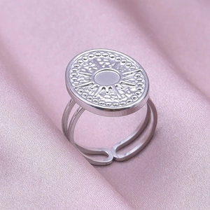 Detailed close-up of a sunburst engraved stainless steel ring on pink silk fabric