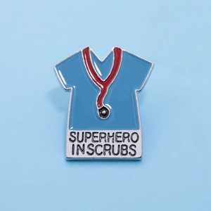 Detail of blue scrubs enamel pin with stethoscope and Superhero in Scrubs text