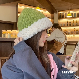 Close-up of women's chunky knit green beanie with thick white faux fur trim on model