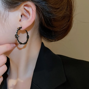 Close-up of vintage black tiger eye hoop earrings with sparkling rhinestones on model