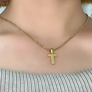 Primo piano di una collana in acciaio al titanio dorato con ciondolo a lettera T