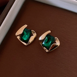 Macro shot of vintage gold earrings with rectangular emerald green gemstone inlays