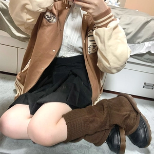 Detailed knit texture of brown y2k style slouchy leg warmers worn with a pleated skirt