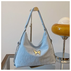 Detail of light blue tote bag featuring golden butterfly hardware and wrinkled texture