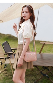 Detail of pink embroidered crossbody bag with floral pattern and butterfly decorations