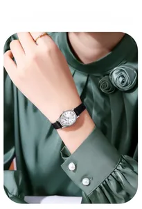 Close-up of minimalist silver oval watch with black leather strap on female wrist