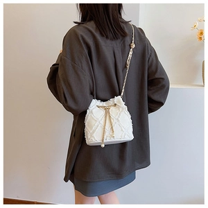 Detailed shot of white tweed crossbody bag with pearl chain and diamond quilted texture