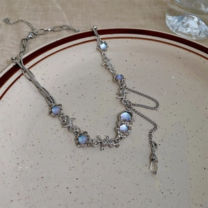 Barbed wire necklace with blue cat's eye stones and crystal pendant on tray