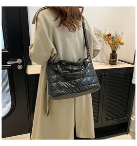 Lifestyle shot of a black quilted down tote bag worn by a model in a khaki trench coat