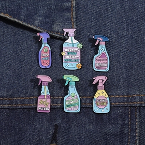 Collection of creative enamel spray bottle pins with humorous text on denim background