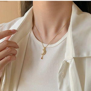 Close-up of gold moon and star pendant necklace with micro-diamonds on a model