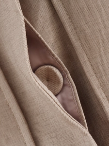 Macro shot of twill fabric with fabric-covered button and detailed stitching on brown jacket