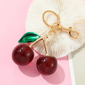 Detailed view of dark red glitter cherry keychain with green leaves and gold lobster clasp