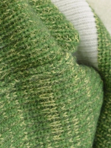 Macro shot of green and yellow marl knit fabric showing soft fiber texture and weave