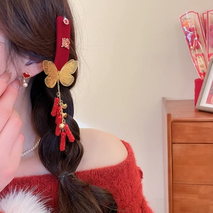 Detail of red velvet butterfly hair clip with gold lettering and firecracker tassel