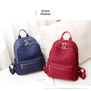 Detail view of quilted Oxford fabric backpacks in navy and burgundy with multiple zippers