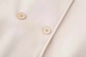 Detail view of pink wool coat showing textured fabric and matching resin buttons