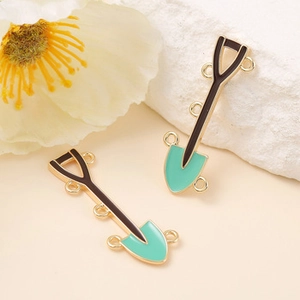 Detail of mini shovel pendants in mint green and black with gold metal frames