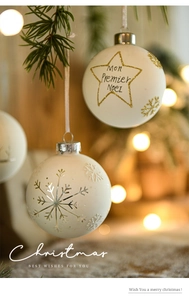 Close-up of cream Christmas ball ornament with snowflake relief on a pine tree branch