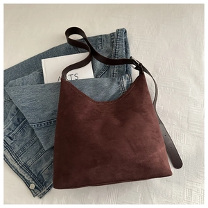 Detail of burgundy matte leather shoulder bag with minimalist finish and soft suede texture