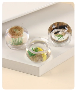 Vue détaillée de mini bocaux à poissons en verre avec sable et décorations aquatiques