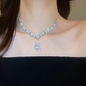 Close-up of elegant silver necklace with sparkling pear-shaped zircon pendant on model