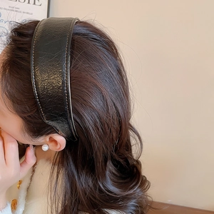 Macro detail of black pleated PU leather headband with contrast brown stitching
