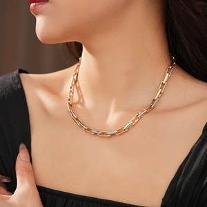 Close-up of interlocking gold and silver chain necklace links with polished finish
