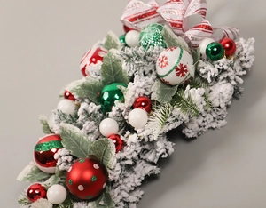 Detail of flocked Christmas teardrop swag with red and green ornaments and a bow