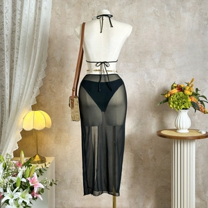 Detail of sheer black mesh beach skirt featuring elegant gold waist chain jewelry