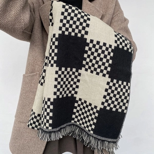 Thick black and white checkerboard scarf with tassel fringe worn by a model