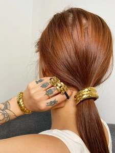 Model wearing a gold metal hair cuff with matching bracelet and ring for a stylish look