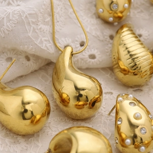 Elegant 18K gold teardrop pendant necklace and stud earrings set on lace fabric