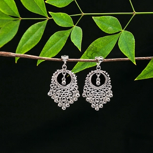 Close-up of vintage tribal hollow-out earrings with metal tassels on a branch